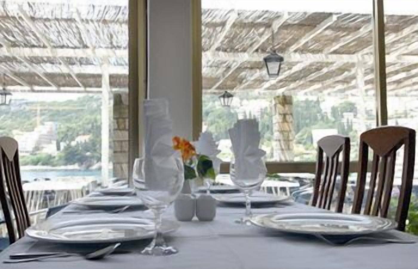 A table set for dining with a view of a body of water and greenery.