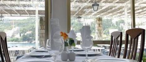 A table set for dining with a view of a body of water and greenery.