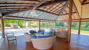 Un espace extérieur aménagé, abrité et doté de meubles en osier et d’une terrasse en bois.