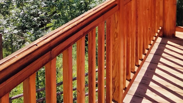 A wooden balcony with a view of a mountainous landscape.