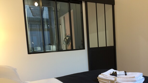 A hotel room with a bed, a window, and a mirror.
