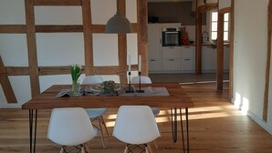 A dining area with a wooden table, white chairs, and a hanging light fixture. - Modern vacation apartment "Lamm" 2 - 3 persons  (Sinsheim)