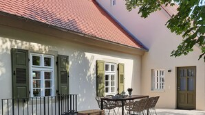 A house with a tiled roof, a patio with a table and chairs, and a potted plant with pink flowers. - Modern vacation apartment "Lamm" 2 - 3 persons  (Sinsheim)