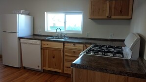 A kitchen with wooden cabinets, a dishwasher, a sink, and a gas stove. - The Red House (Rapid City)
