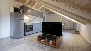 Una cocina moderna con horno integrado, refrigerador y mueble de entretenimiento de madera con televisor de pantalla plana.