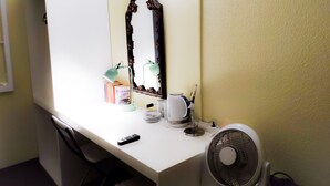 Ein weißer Schreibtisch mit Spiegel, Lampe, Ventilator und einigen Büchern.