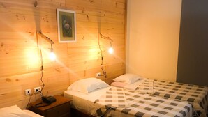 Ein Zimmer mit zwei Betten, jeweils mit kariertem Bettbezug und weißen Kissen. An den Nachttischen stehen Lampen und ein gerahmtes Bild hängt an der Wand.