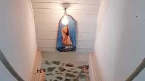 A narrow stairway with a ceiling fan, a patterned wall, and a rope barrier.