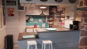 A kitchen with a blue tiled backsplash, a coffee machine, and a sink.