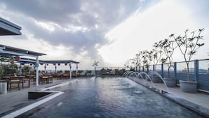 Ein Pool auf dem Dach mit Sitzgelegenheit und Topfpflanzen.