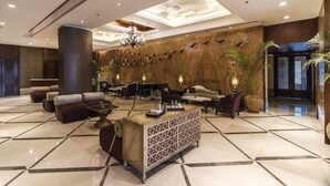 Eine geräumige Lobby mit einer Rezeption, Sofas und einer Kristallleuchtre.'