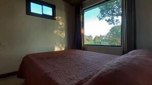 Ein Schlafzimmer mit großem Fenster, einem Bett und einem kleinen Tisch.