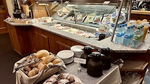 Mostrador de buffet amb diversos plats, racó de cafè i amples de botelles d'aigua.