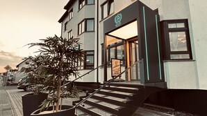 Entrada d'hotel amb una escala que condueix a la porta, una planta en test i un cel serè.