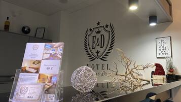 Een hotel receptie met een receptiebalie, een decoratieve bol en een wandbordje met de naam en het logo van het hotel.