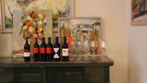 Disposición para cata de vinos con botellas y copas sobre una mesa, rodeada de pinturas abstractas.
