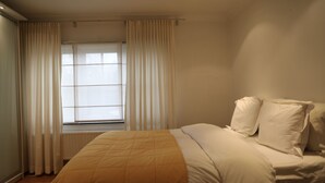 Un dormitorio con cama, cortinas y ventana.