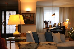A cozy living room with a sofa, a lamp, a piano, and a Christmas tree. - Charmante Vakantiewoning Oudsbergen (Opglabbeek)