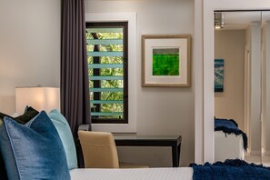 Habitación de hotel con cama, escritorio, ventana con persianas e imagen en un marco en la pared.