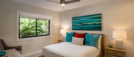 Une chambre à coucher avec un lit, un ventilateur de plafond, une fenêtre donnant sur un paysage verdoyant, un tableau au mur et des lampes de chevet.
