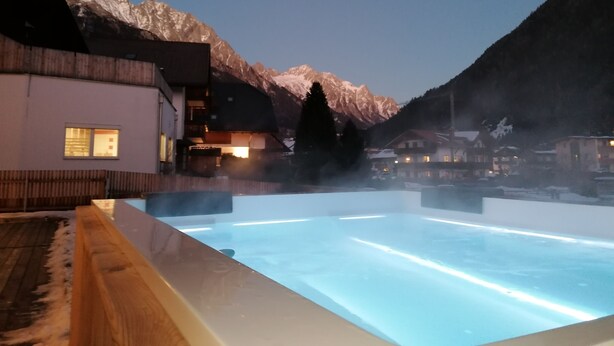 A pool area with a view of snow-capped mountains and a building with multiple windows. - Deluxe Apartment With Large Balcony, Woodn Interior (Antholz Mittertal)