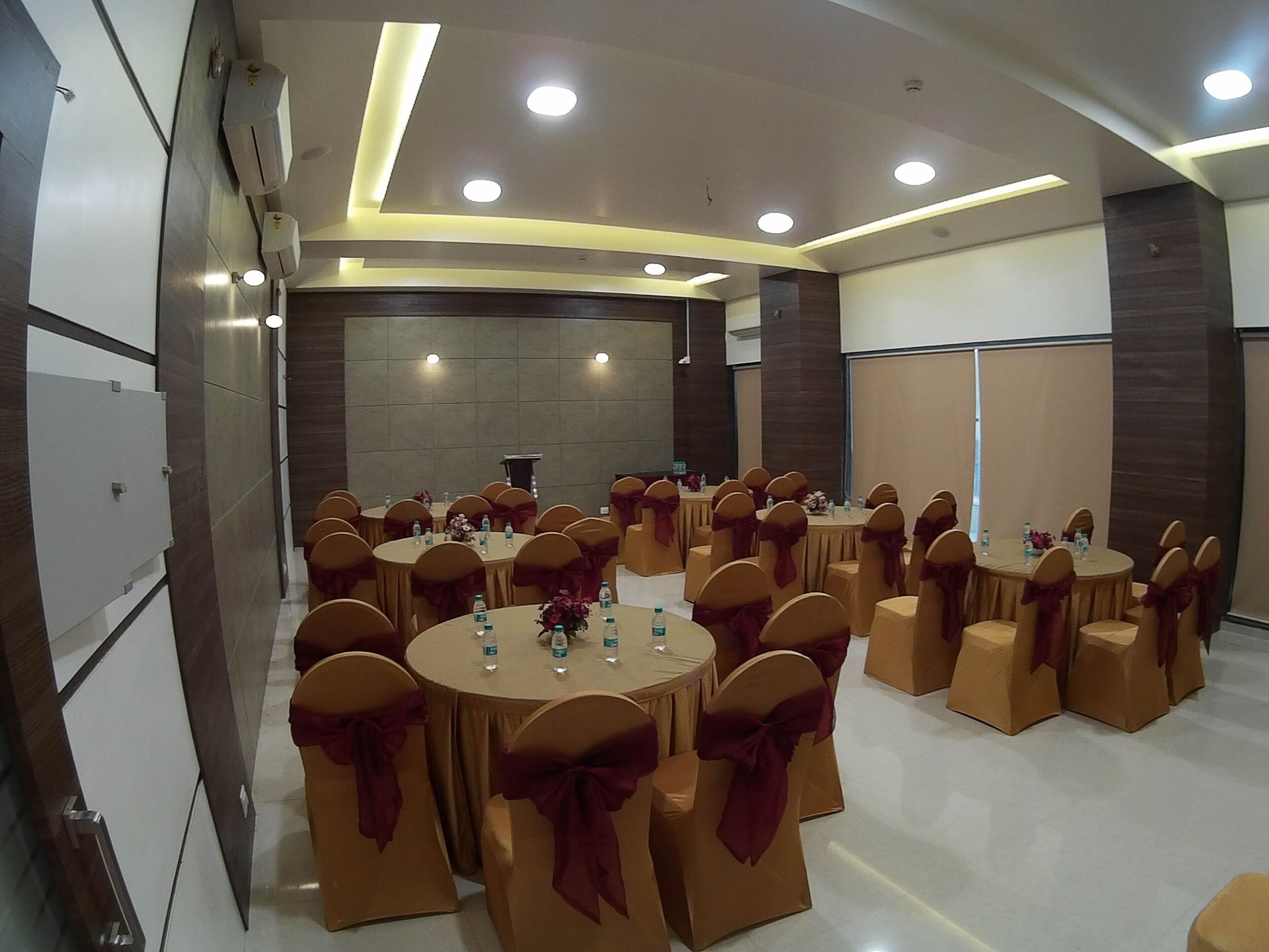 A conference room with round tables, chairs with red sashes, and a podium.