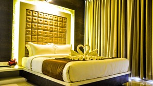 A hotel room with a large bed, a tufted headboard, and a decorative swan on the bed. - Rudra Shelter International (Vasai)
