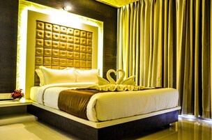 Una habitación de hotel con una cama grande, un cabecero capitonado y un cisne decorativo sobre la cama.