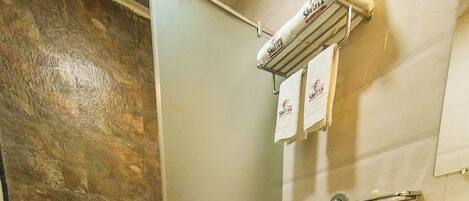 A bathroom with a toilet, a sink, and a shower. There are towels hanging on a rack.