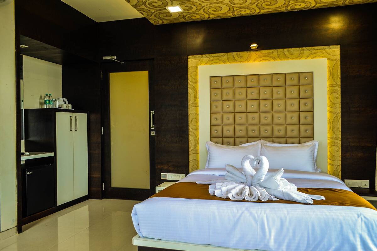 A hotel room with a bed, a wardrobe, a bathroom, and a decorative headboard.