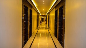 A long, narrow hotel corridor with a reflective floor and doors on both sides. - Rudra Shelter International (Vasai)