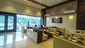A modern dining area with a central island, seating, and a view of the street. - Rudra Shelter International (Vasai)