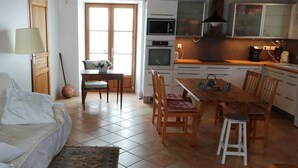 Un salon confortable avec un canapé, une table à manger et des chaises, ainsi qu’un coin cuisine doté de placards et d’appareils électroménagers.