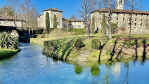 A clear river with stone buildings and a tower in the background.