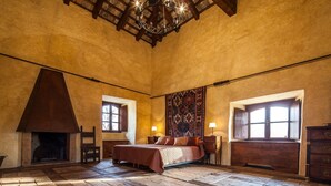 A spacious bedroom with a large bed, a fireplace, and a large window with a view.