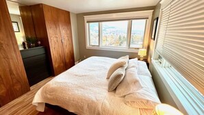 Una camera da letto con un letto grande, una finestra con persiane e vista sull'esterno.