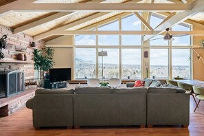 A spacious living room with a large sectional sofa, a fireplace, and a view of the mountains through large windows. - Expansive Luxury in Central Home With Downtown Views (Boulder)