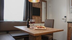 A dining area with a wooden table, a bottle of wine, and a glass of red wine.