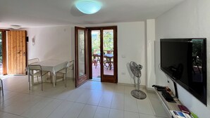 Una habitación con una mesa de comedor, sillas, un televisor y un ventilador.