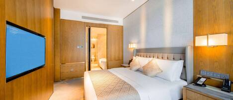 Une chambre d’hôtel avec un grand lit, des lampes de chevet, une table de chevet avec un téléphone et un téléviseur fixé au mur.