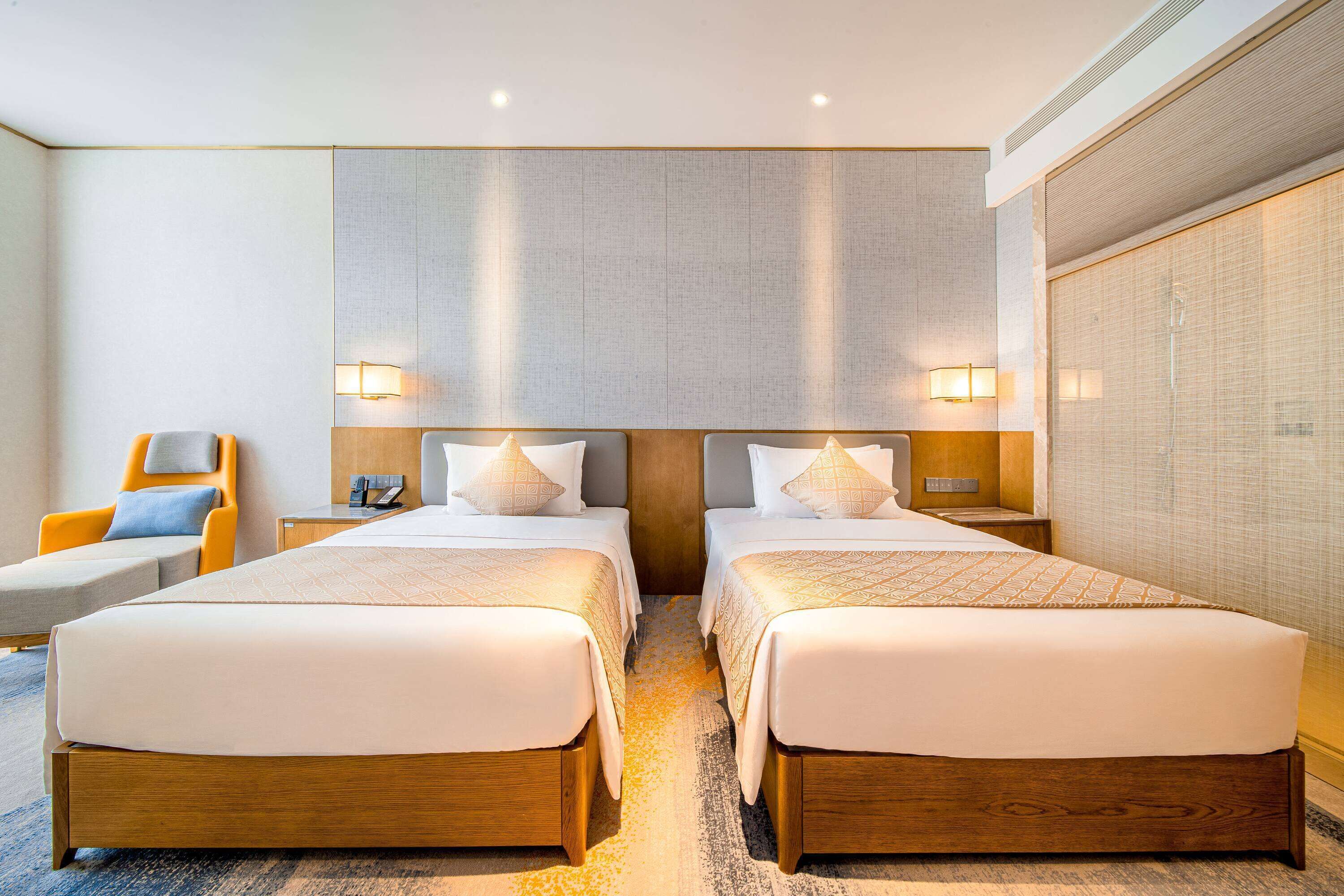 A hotel room with two beds, a sofa, and a nightstand.
