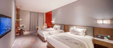 A hotel room with two beds, a TV, a desk, and a chair.