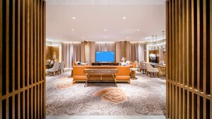Una sala de estar moderna con un televisor de pantalla plana grande, un sofá naranja y una alfombra estampada.