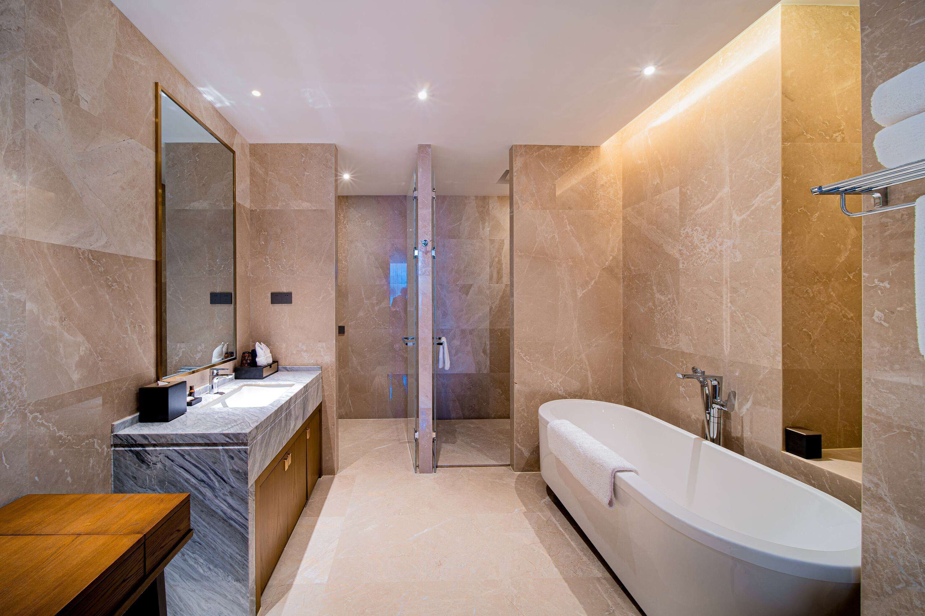 Un baño moderno con tocador de mármol, bañera independiente y ducha con cerramiento de vidrio.