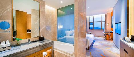 A modern hotel bathroom with a large mirror, a bathtub, and a vanity with a sink.