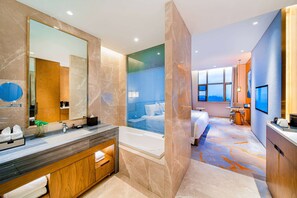 Enjoy a spacious room with a large bed, separate shower area, and sitting area with a table and chair.
