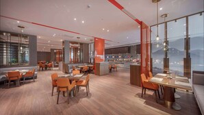 Un restaurante moderno con suelo de madera, sillas anaranjadas y una zona de bar con vistas a las montañas.