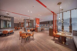 Experience the hotel's spacious lobby, featuring dining tables and chairs, large windows with mountain views, and modern design.