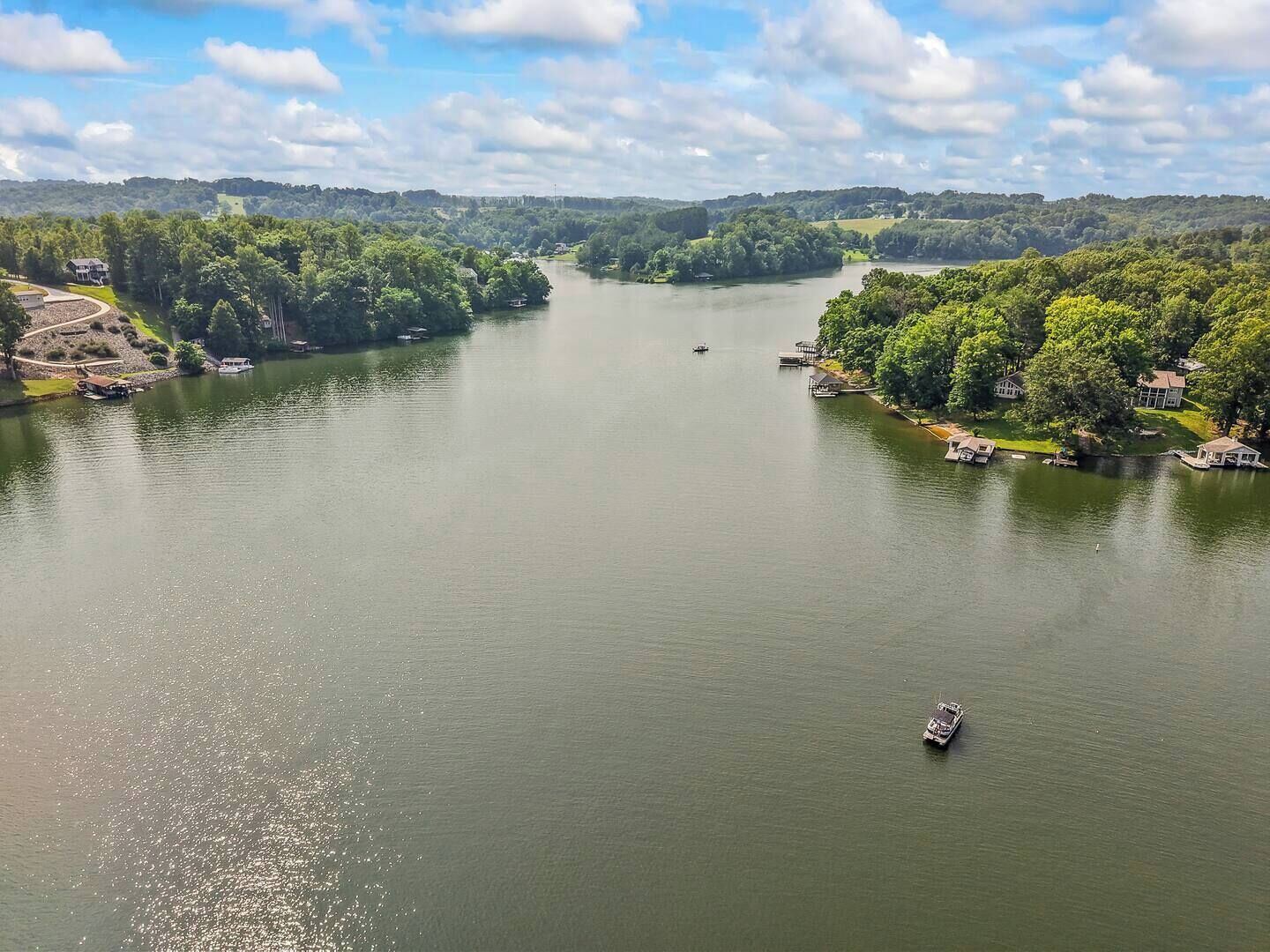 A river with boats, surrounded by lush greenery and houses.