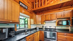 Una cocina moderna con armarios de madera, estufa de acero inoxidable, microondas y cafetera.